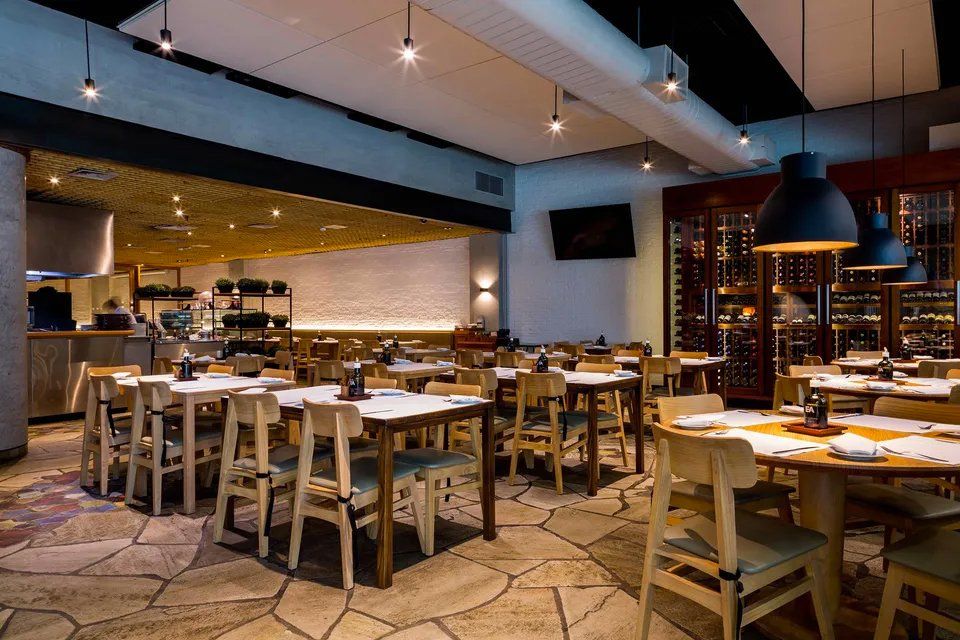 Uma grande sala de jantar com mesas e cadeiras em um restaurante.
