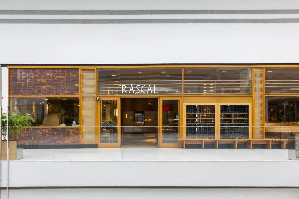 A frente de um restaurante chamado malandro com porta de madeira.