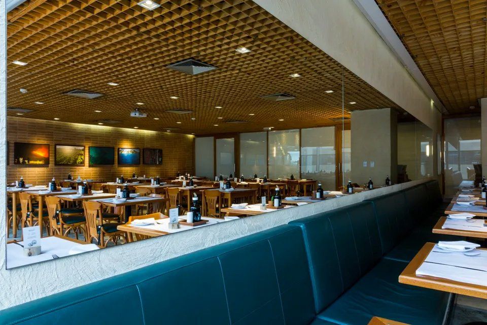 Um restaurante com mesas e cadeiras e um banco comprido.