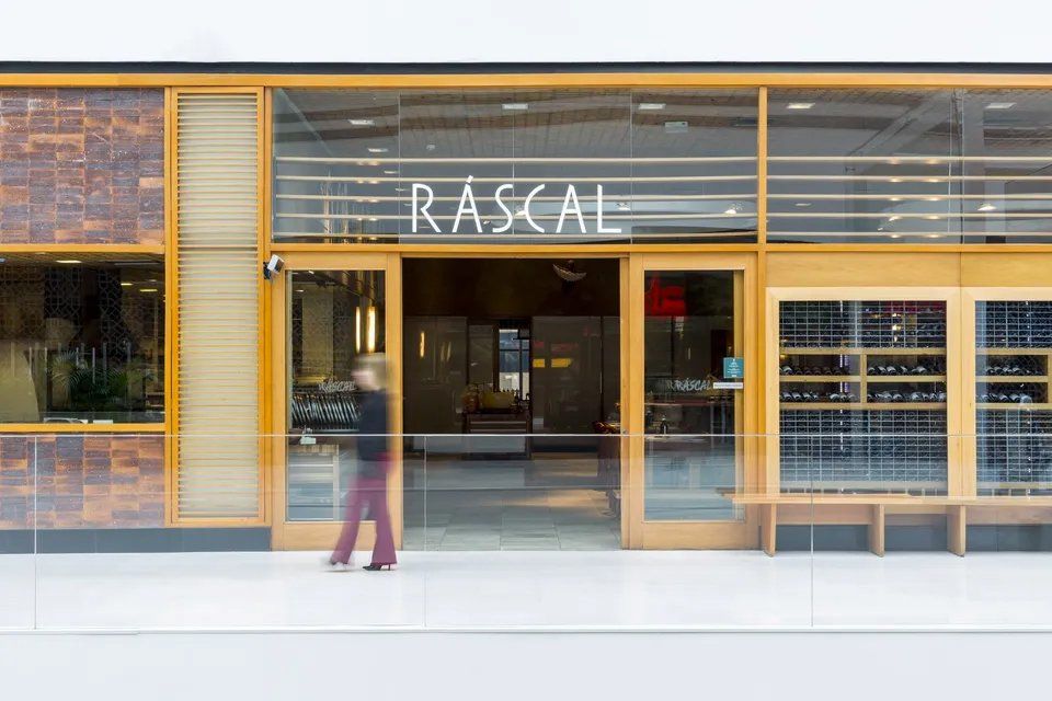 Uma mulher está andando em frente a uma loja chamada malandro.