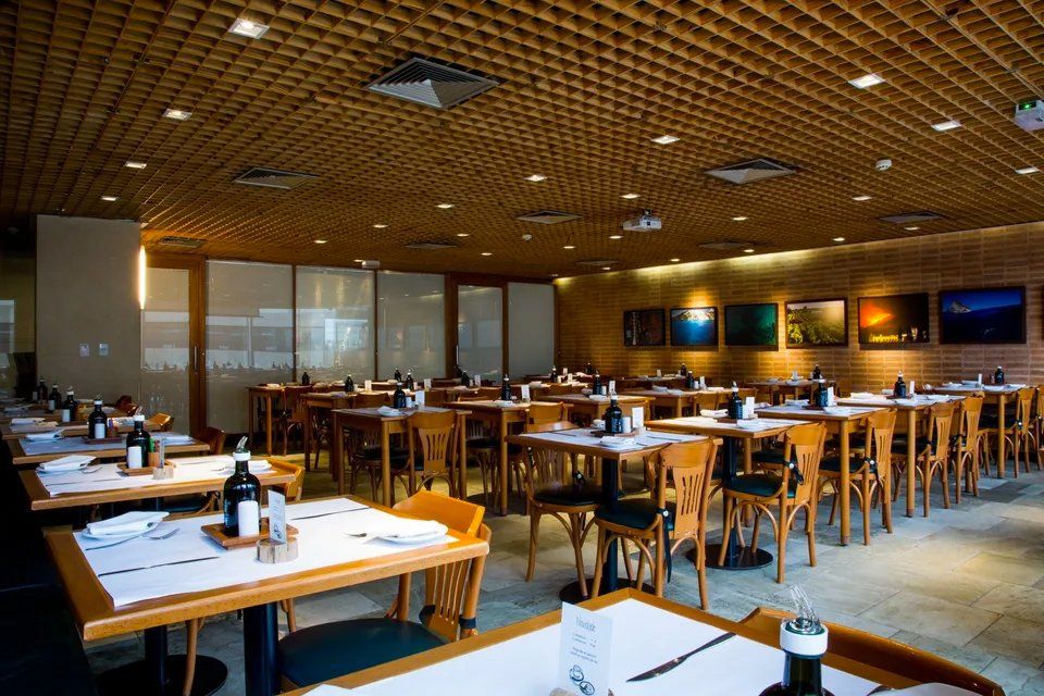 Um restaurante com mesas e cadeiras e teto de madeira