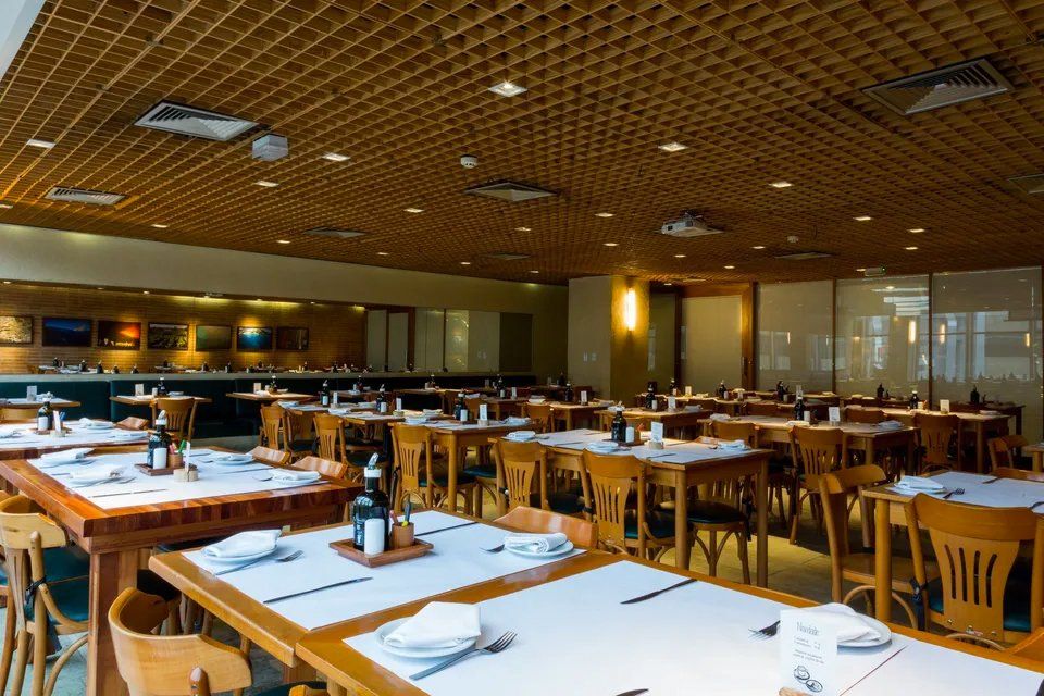 Uma grande sala de jantar com mesas e cadeiras e teto de madeira