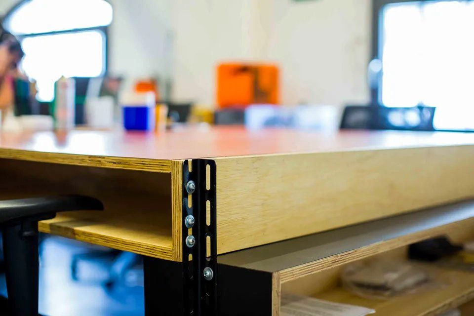 Uma mesa de madeira com uma prateleira embaixo em uma sala.