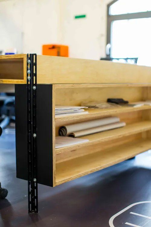 Uma mesa de madeira com prateleiras embaixo em uma sala.