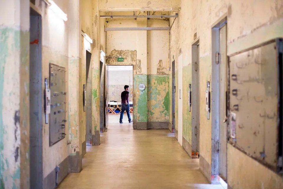 Um homem está andando por um longo corredor de um prédio.