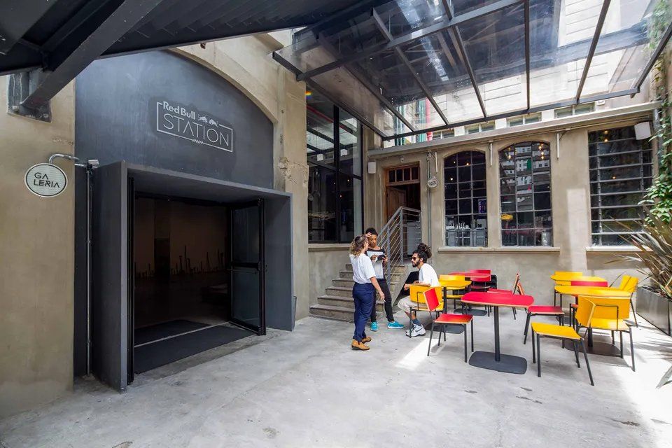 Um grupo de pessoas do lado de fora de um prédio com mesas e cadeiras.