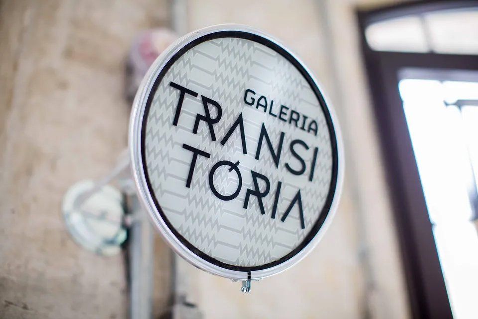 Uma placa que diz galeria transitoria está pendurada na parede.