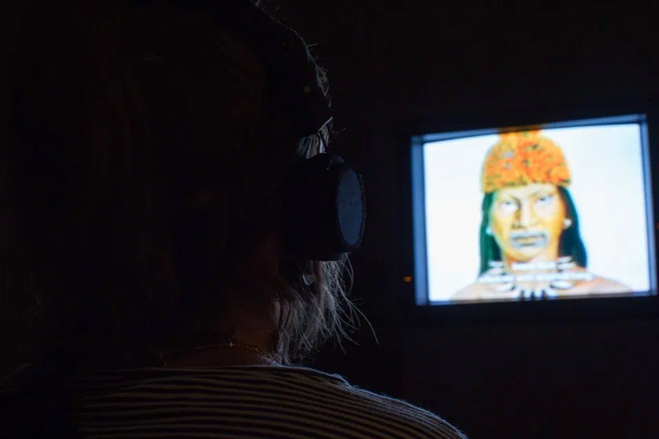 Uma mulher usando fones de ouvido está assistindo a um vídeo na televisão.