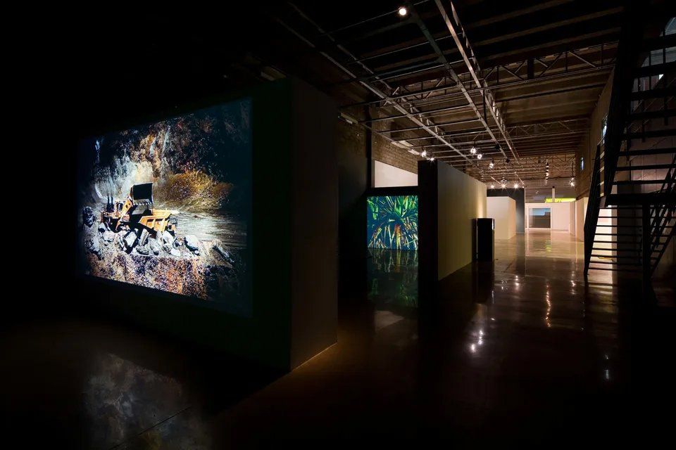 Um corredor escuro com uma escada e algumas pinturas na parede.