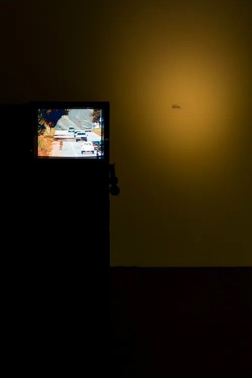 Uma televisão está em um quarto escuro próximo a uma parede.