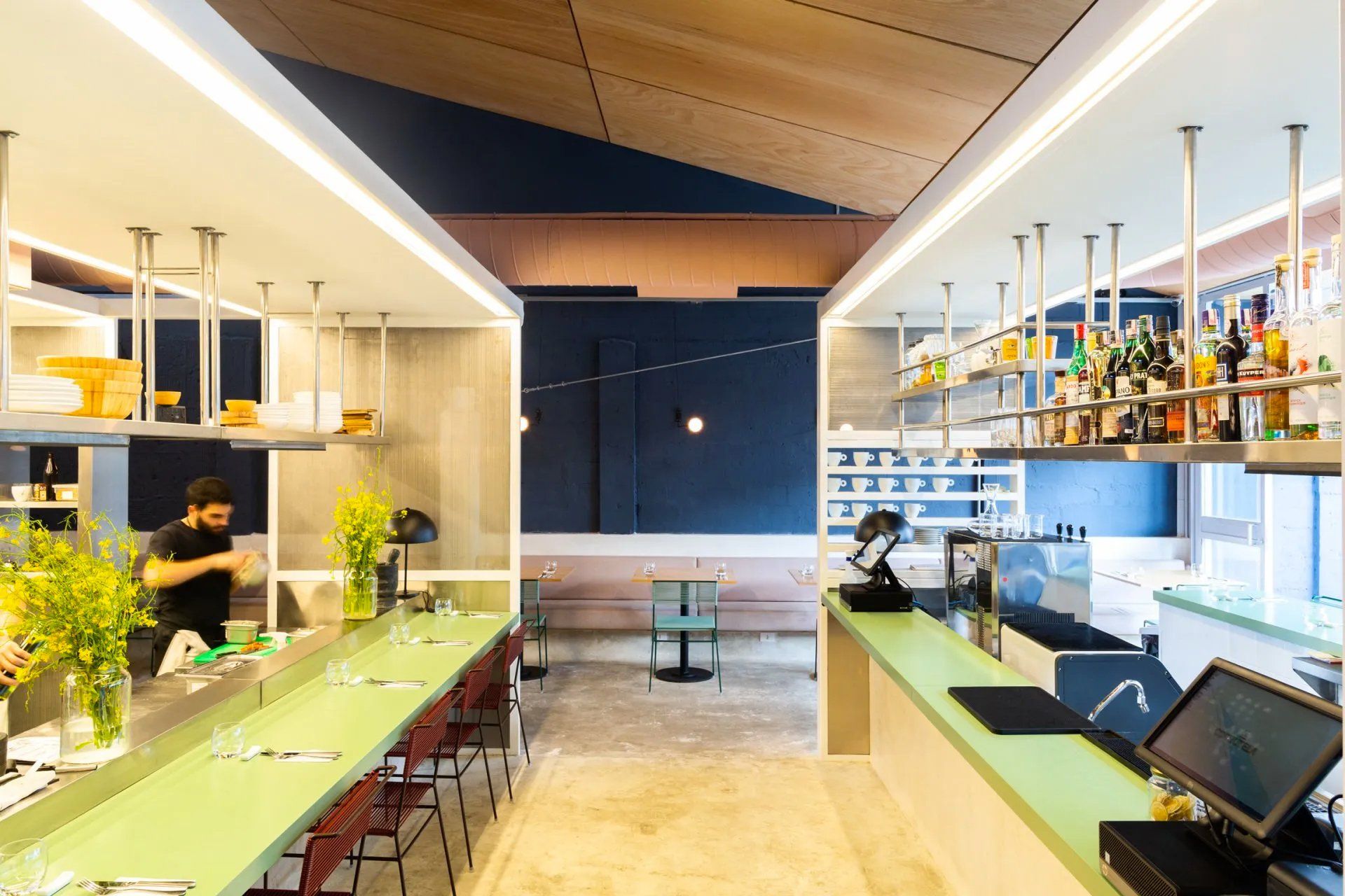 Um restaurante com um longo balcão verde e um bar.