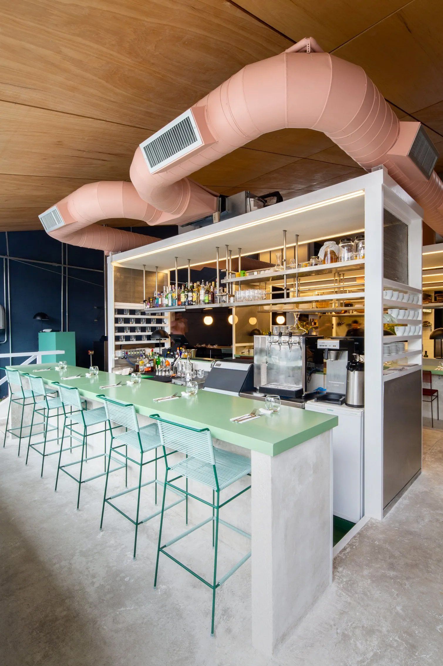 Um restaurante com um longo bar e bancos.