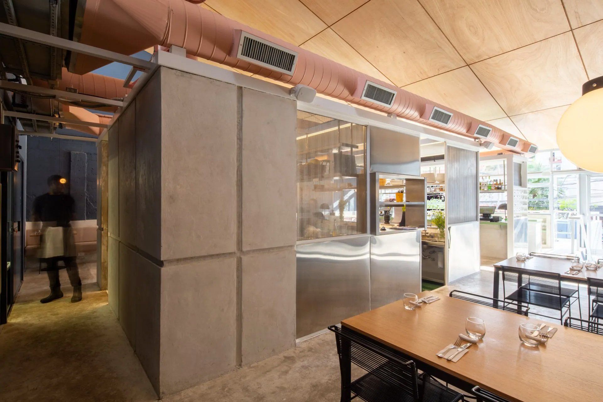 Um restaurante com porta de vidro deslizante entre a cozinha e a sala de jantar.