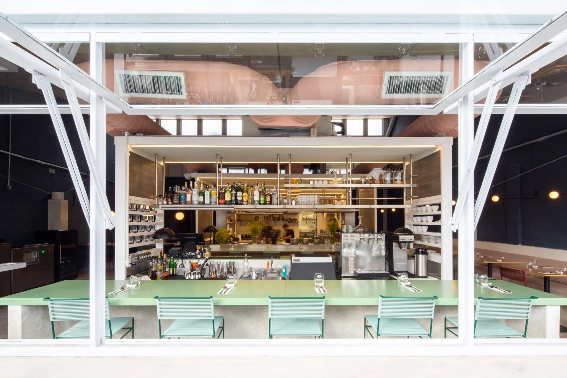 O interior de um restaurante com mesas e cadeiras e um bar.