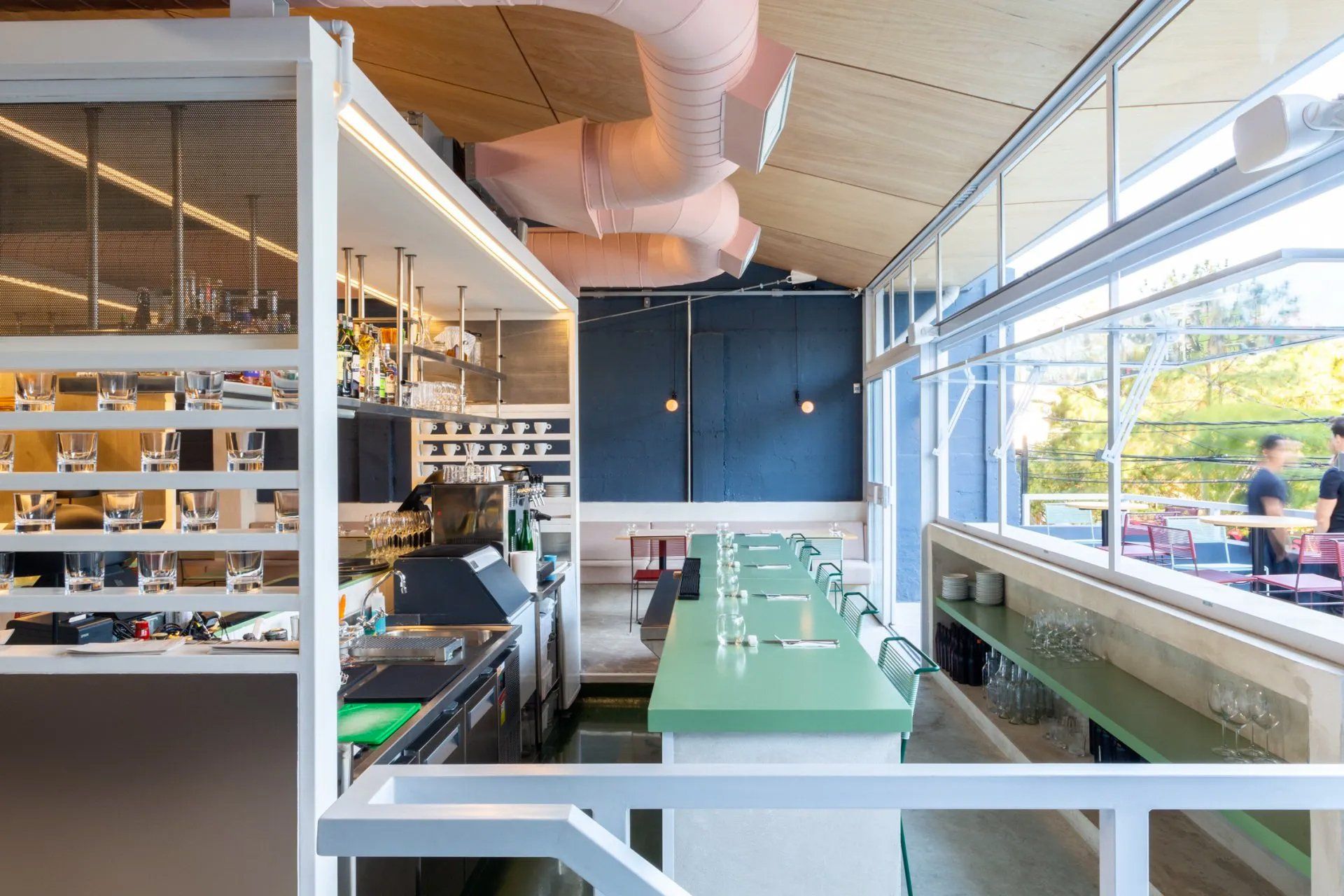 Um restaurante com mesa verde e grade branca.