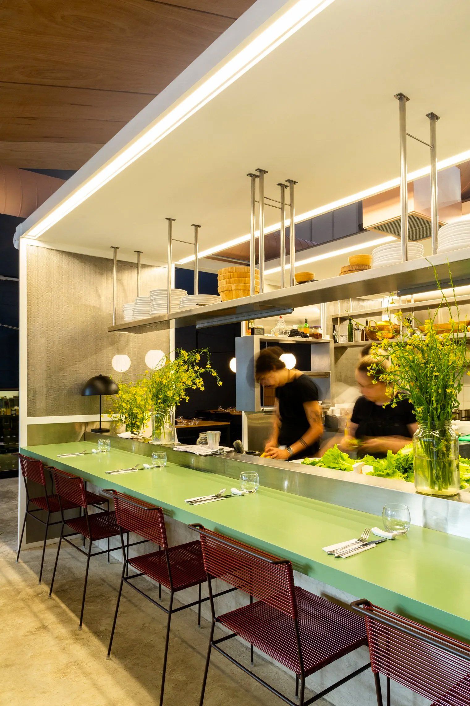 Um restaurante com um longo balcão verde e cadeiras vermelhas.