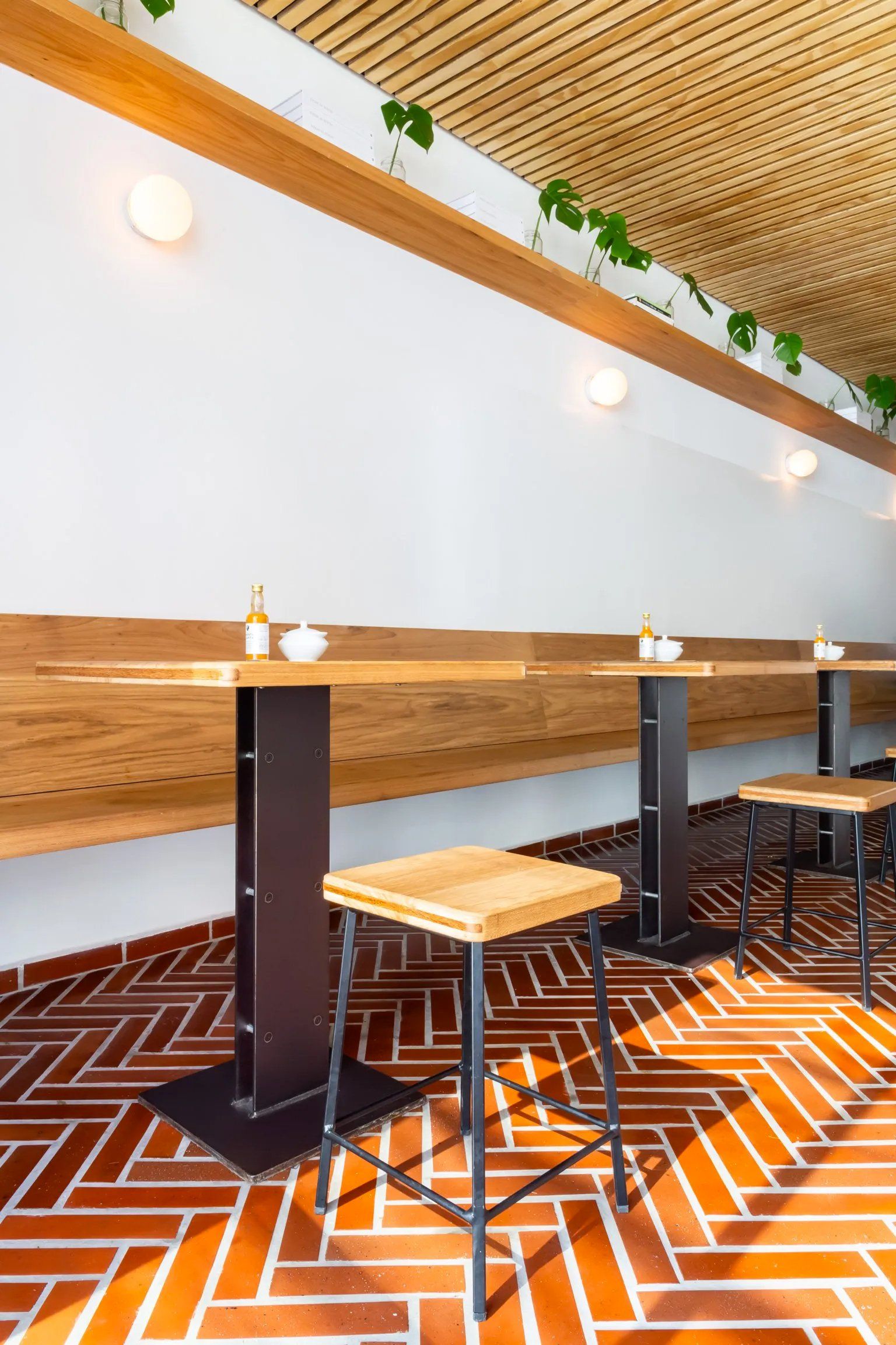 Um restaurante com mesas e bancos e piso em espinha.