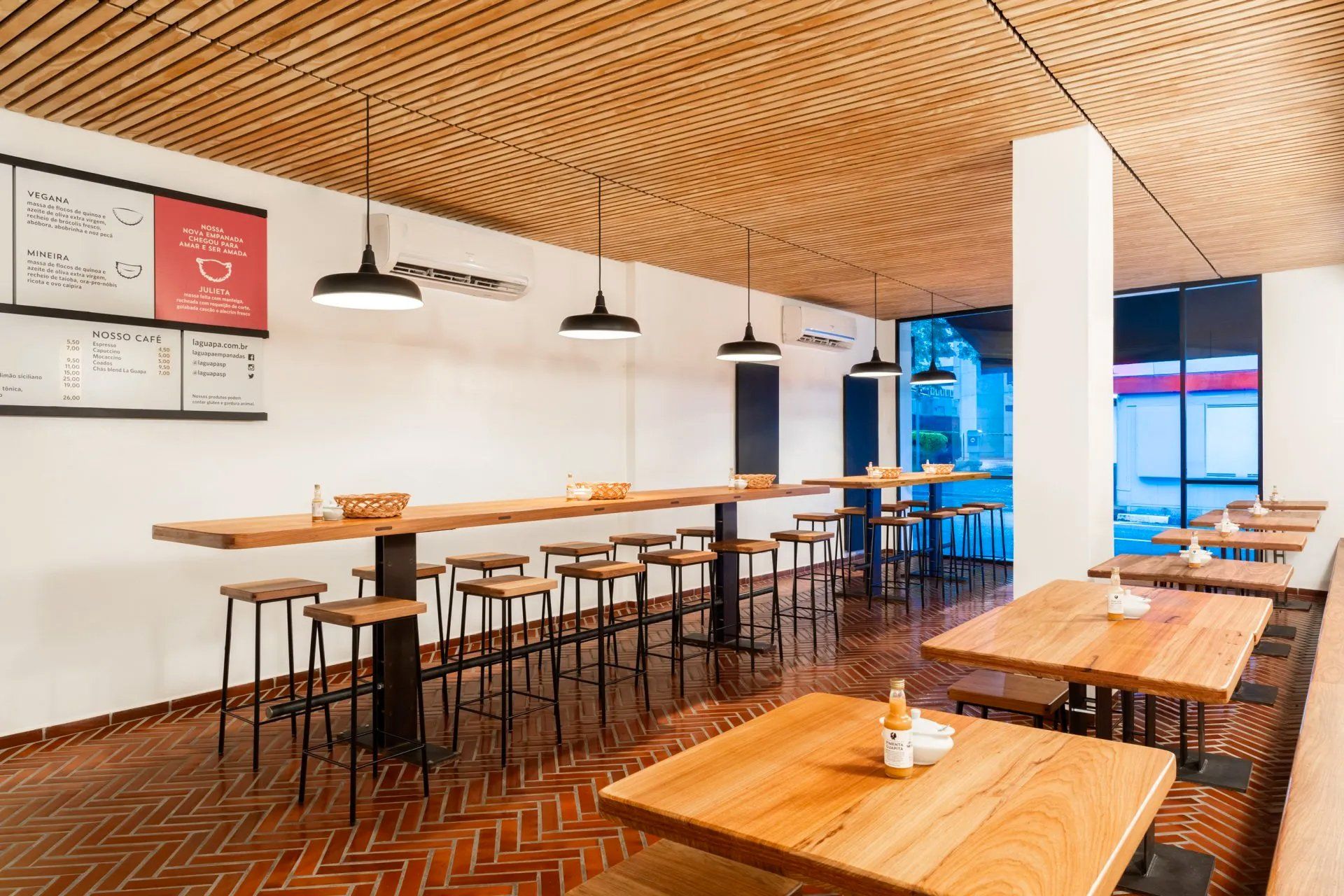 Um restaurante repleto de mesas e bancos de madeira.