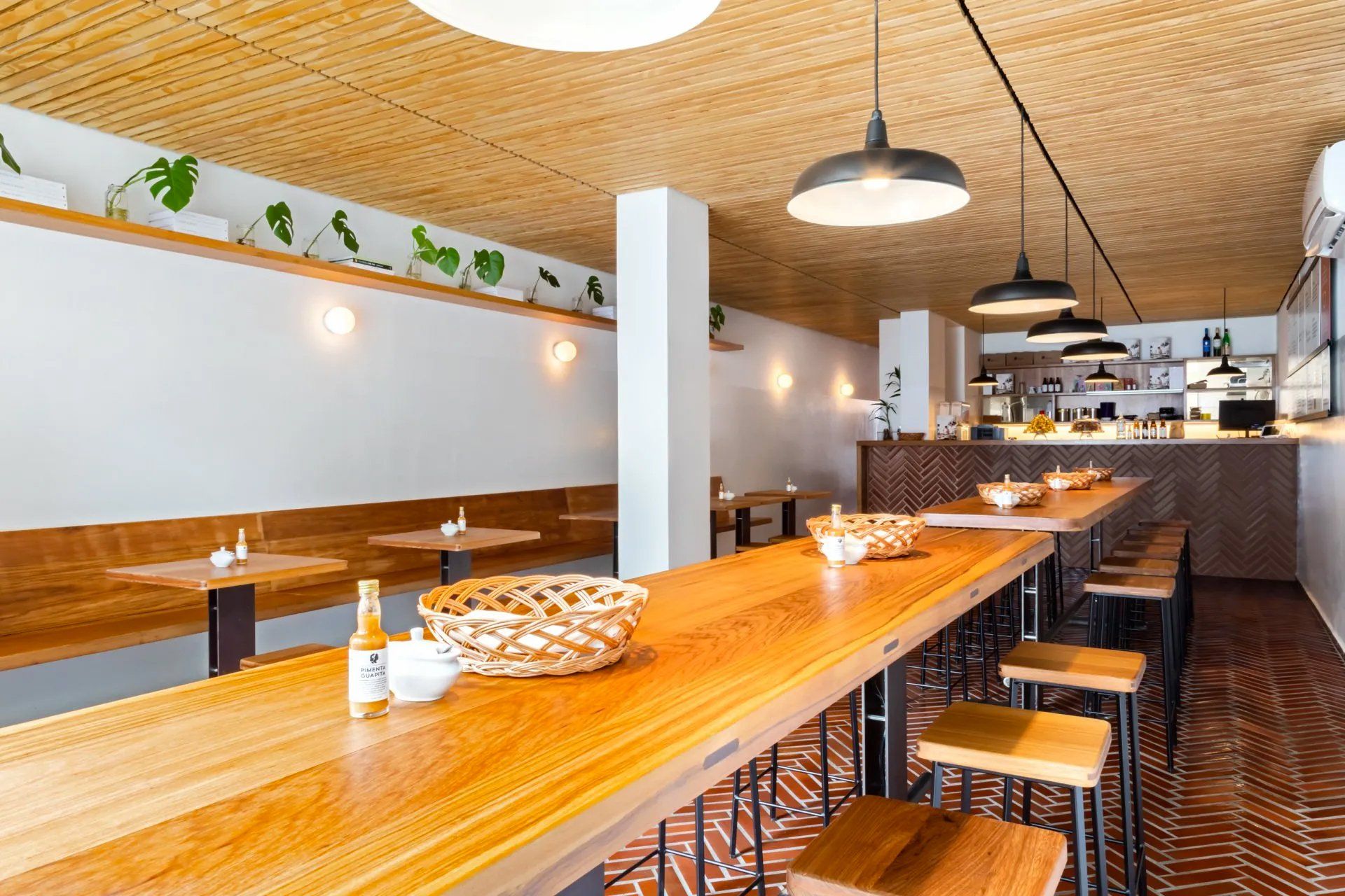 Um restaurante com uma longa mesa de madeira e bancos.