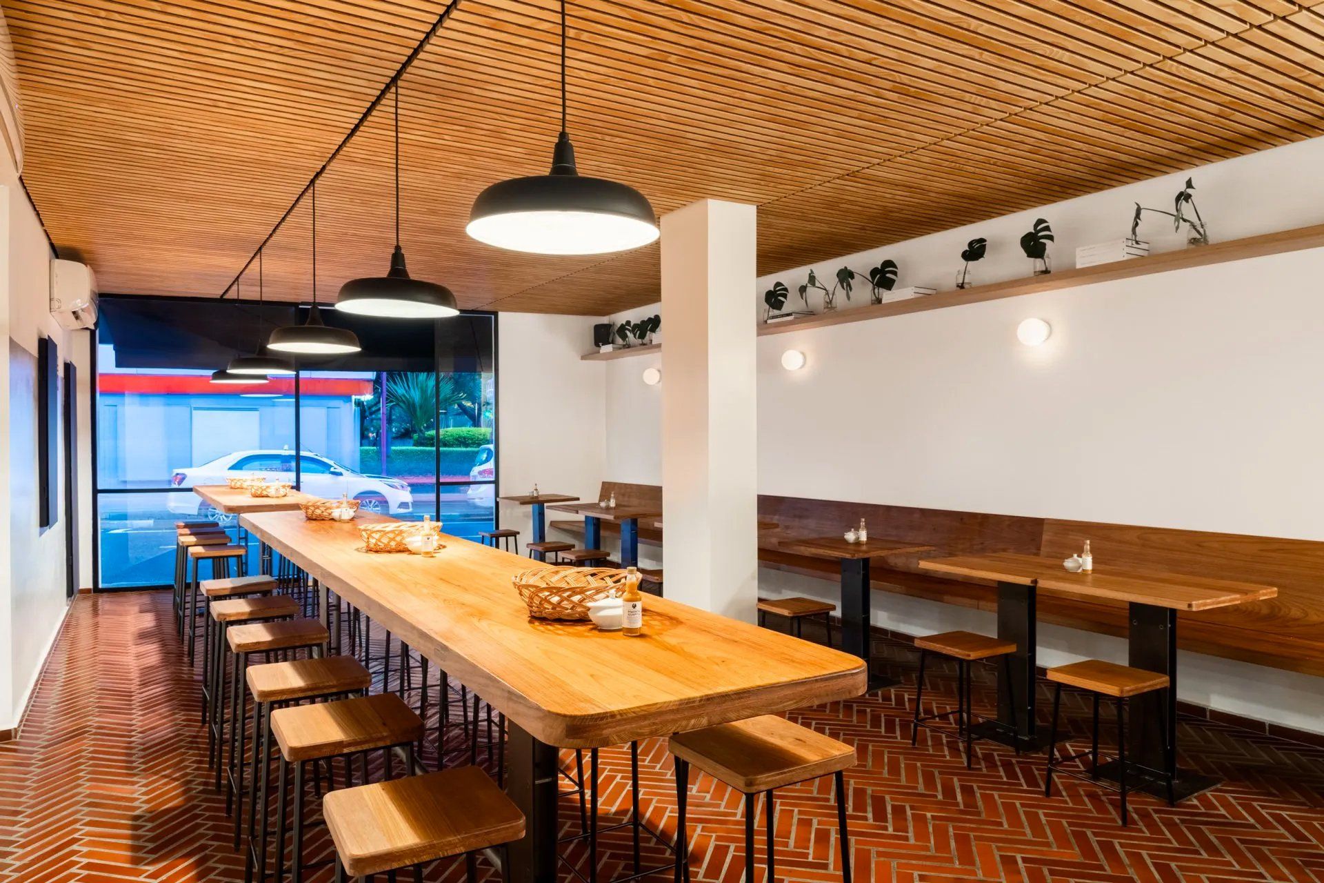 Um restaurante com uma longa mesa de madeira e bancos.