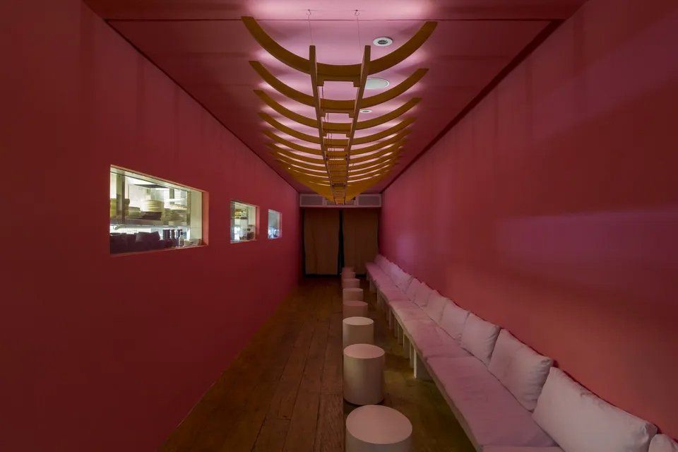 Um longo corredor com paredes rosa e móveis brancos