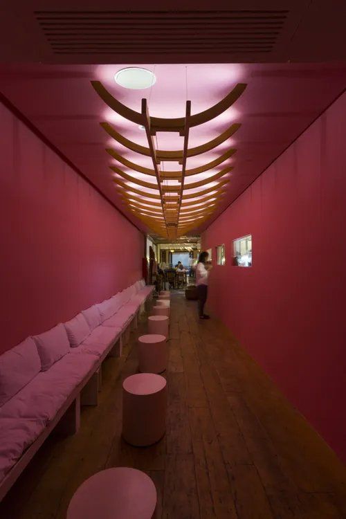 Um longo corredor com paredes rosa e móveis rosa