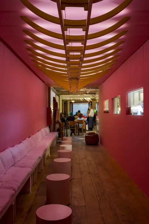 Um longo corredor com paredes rosa e piso de madeira