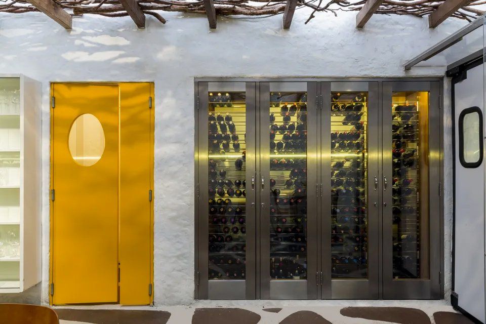 Uma porta amarela está ao lado de uma fileira de portas de aço inoxidável.