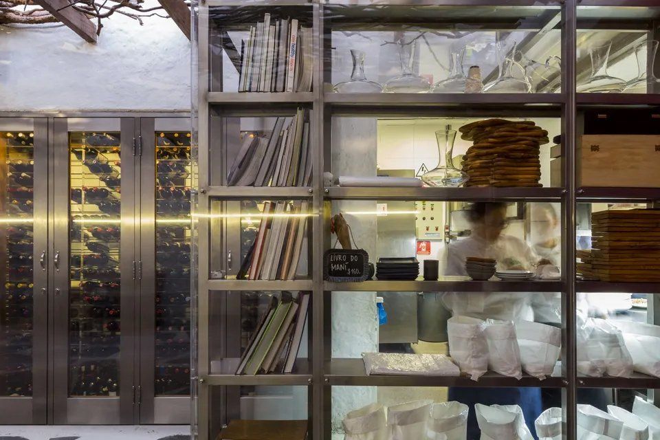 Uma cozinha com muitas prateleiras e uma pessoa ao fundo.