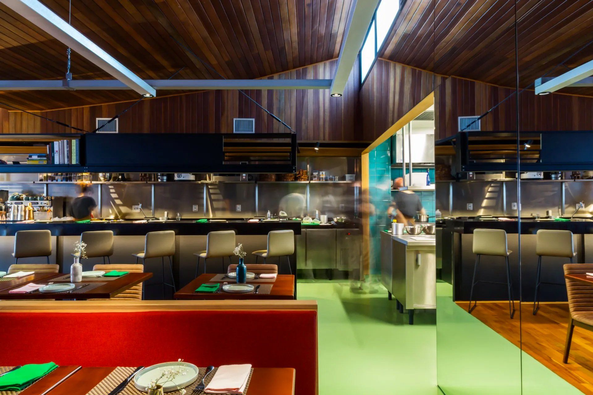 Um restaurante com mesas e cadeiras e uma cozinha ao fundo