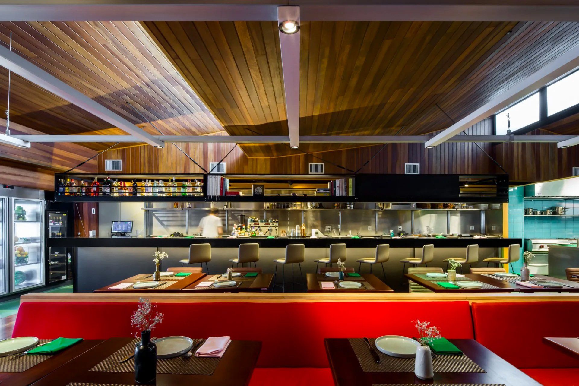 Um restaurante com mesas e cadeiras e uma cozinha ao fundo