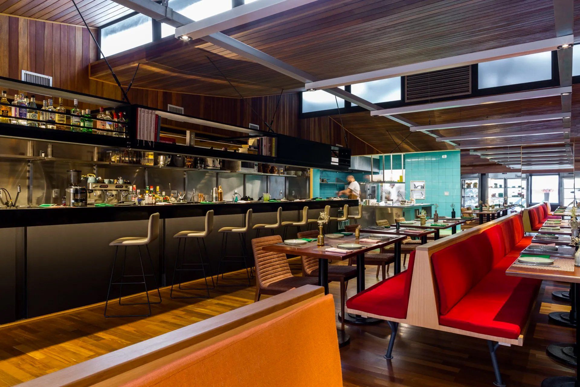 Um restaurante com mesas e bancos e um bar.