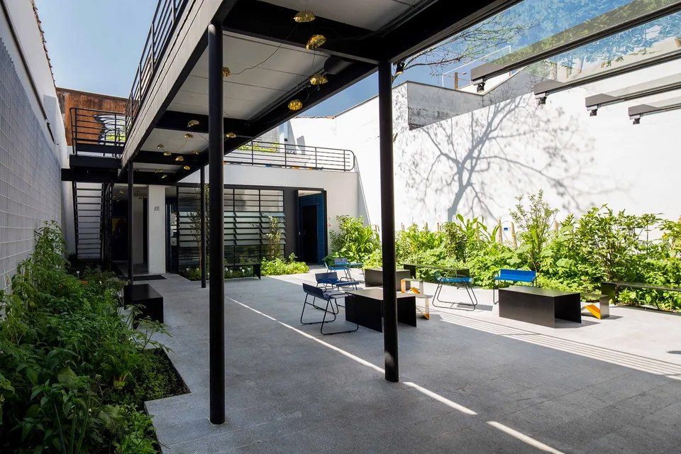 Uma passarela coberta entre dois prédios com cadeiras e mesas.