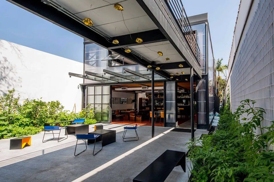 Um pátio com cadeiras e mesas em frente a um prédio.