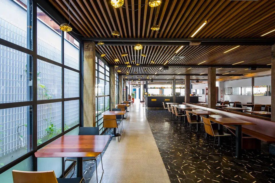 Um restaurante com mesas e cadeiras e muitas janelas.