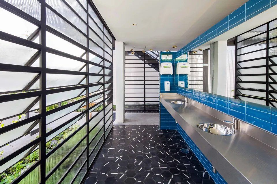 Um banheiro com azulejos azuis e pias de aço inoxidável