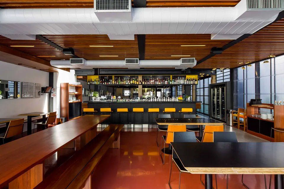 Uma grande sala com mesas e cadeiras e um bar.