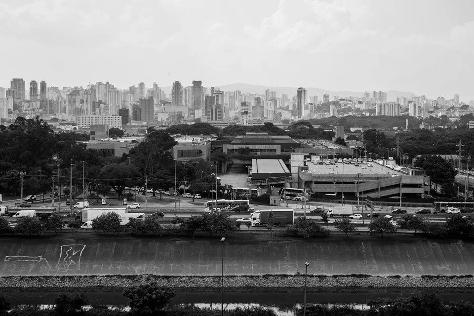 Uma foto em preto e branco do horizonte de uma cidade com um rio em primeiro plano.
