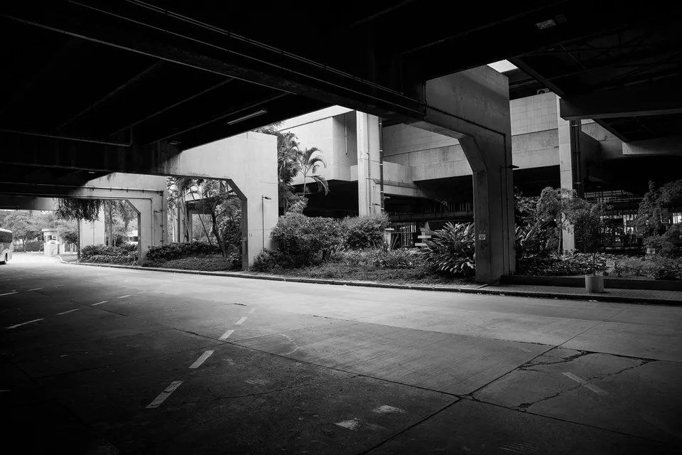 Uma foto em preto e branco de uma rua vazia debaixo de uma ponte.