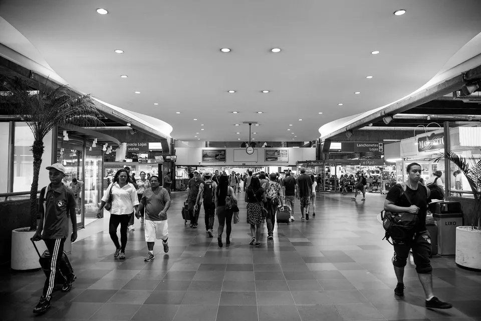 Uma foto em preto e branco de pessoas andando em um shopping.