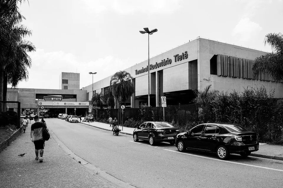 Uma foto em preto e branco de um prédio com carros estacionados em frente.