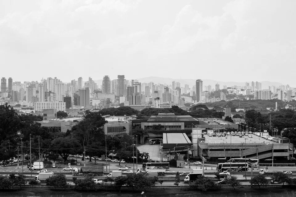 Uma foto em preto e branco do horizonte de uma cidade com um rio em primeiro plano.