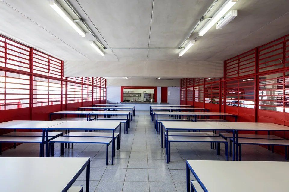 Um refeitório escolar vazio com mesas e bancos