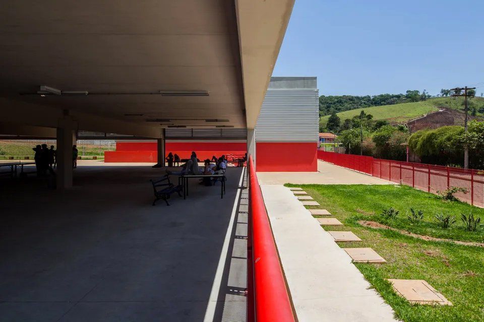 Vista de um prédio a partir de uma varanda com grade vermelha.
