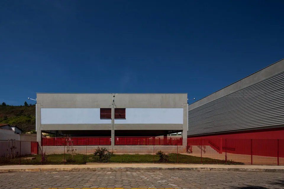 Um grande edifício com uma cerca vermelha e um céu azul ao fundo.