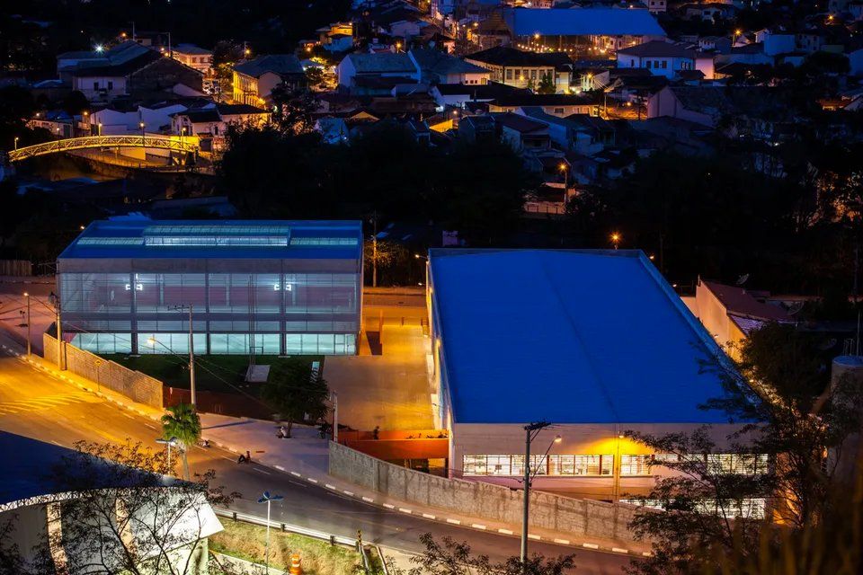 Um grande edifício com telhado azul fica iluminado à noite.