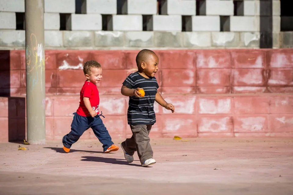 Dois meninos estão brincando com uma bola em um parque.