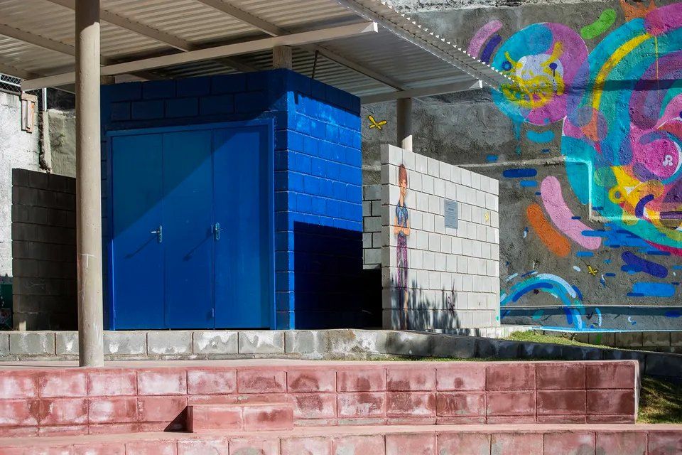 Um prédio azul com um mural colorido ao lado.