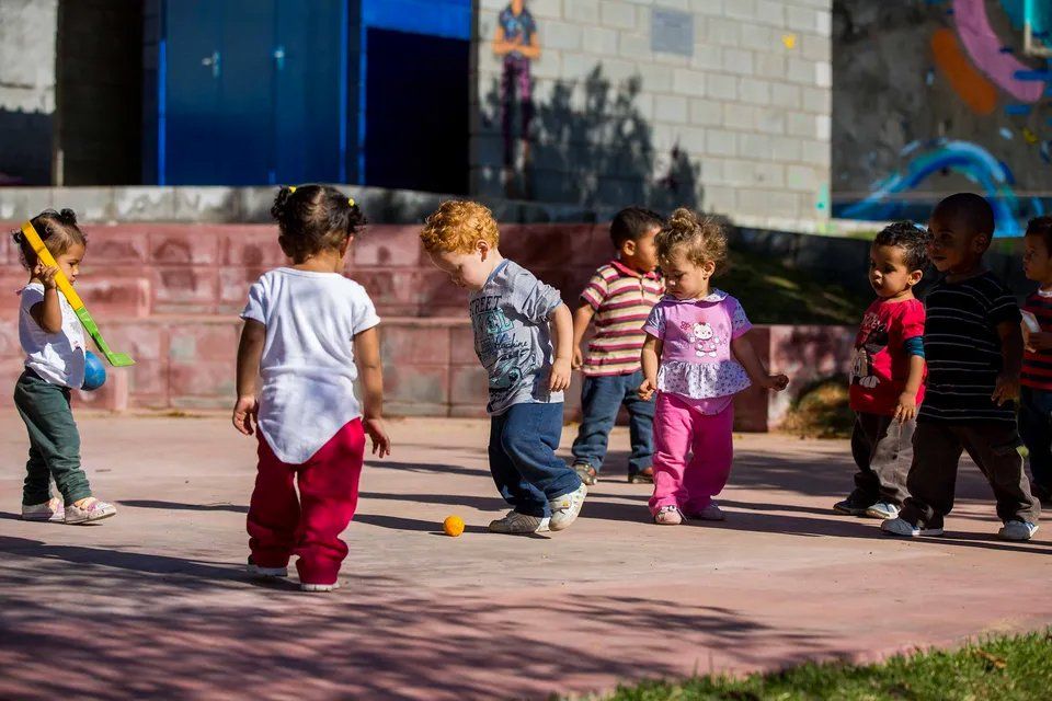 Um grupo de crianças está brincando com uma bola em um playground.