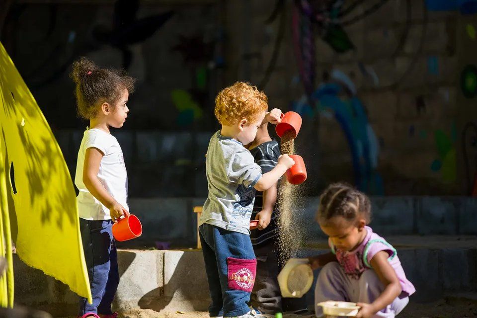 Um grupo de crianças está brincando em uma caixa de areia.
